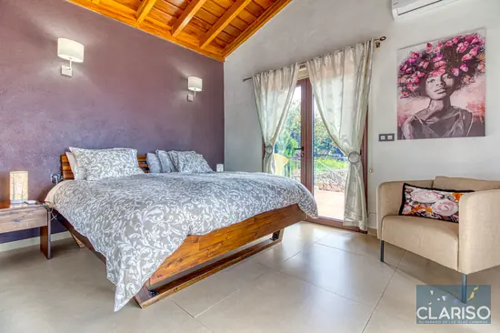 Seitlicher Blick ins Hauptschlafzimmer von Casa El Peral – Ferienhaus in Puntagorda, La Palma – mit großem Doppelbett, Sessel und viel Tageslicht